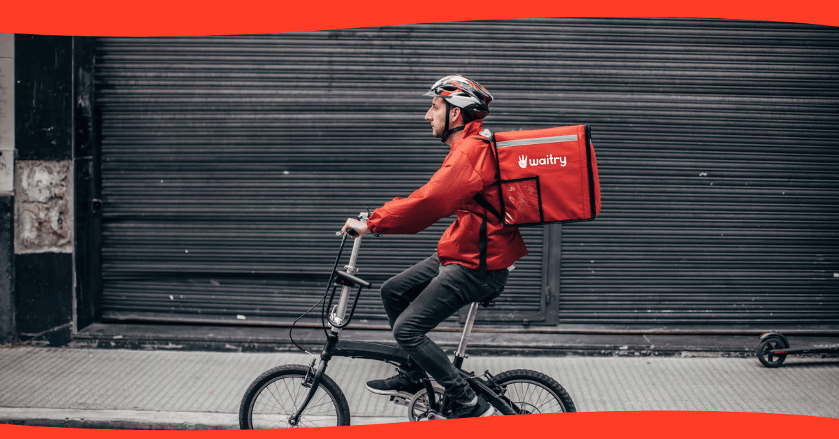 Repartidor en bicicleta con una mochila de delivery roja
