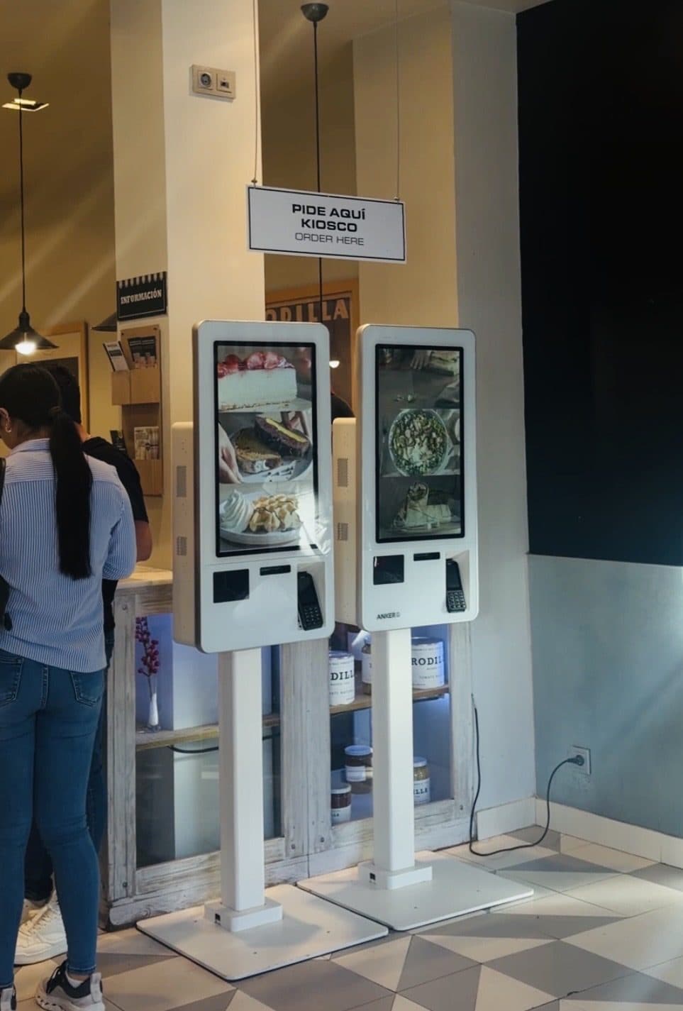 Dos kioscos de autoservicio de Waitry en un local de Rodilla con el cartel "Pide aquí"