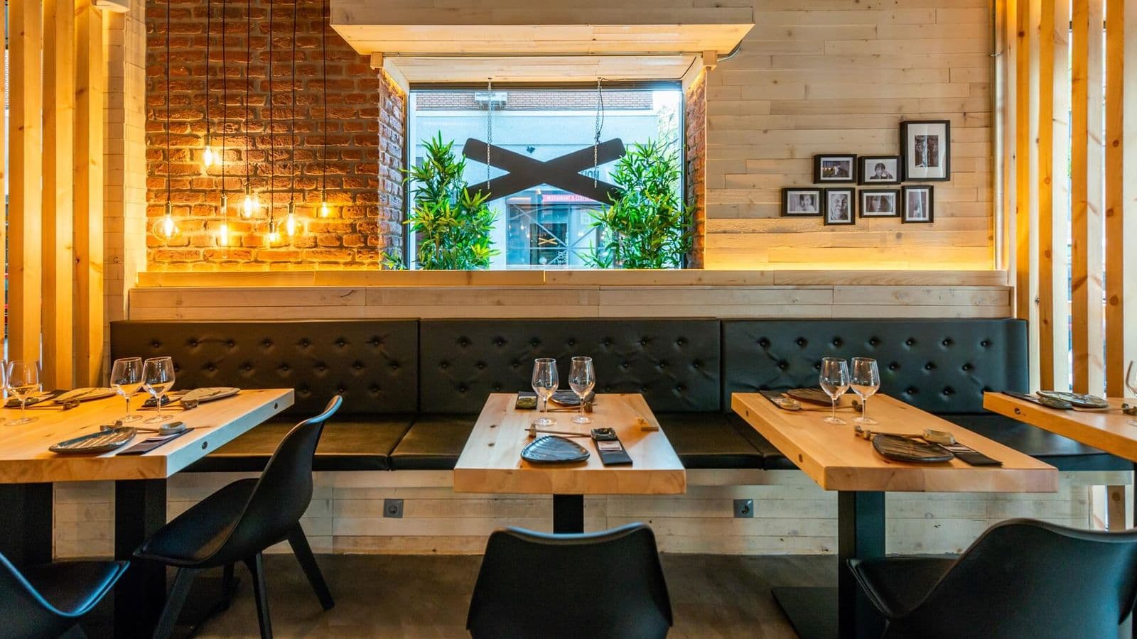 Interior de un restaurante Sibuya con mesas de madera y la X de la marca en la pared